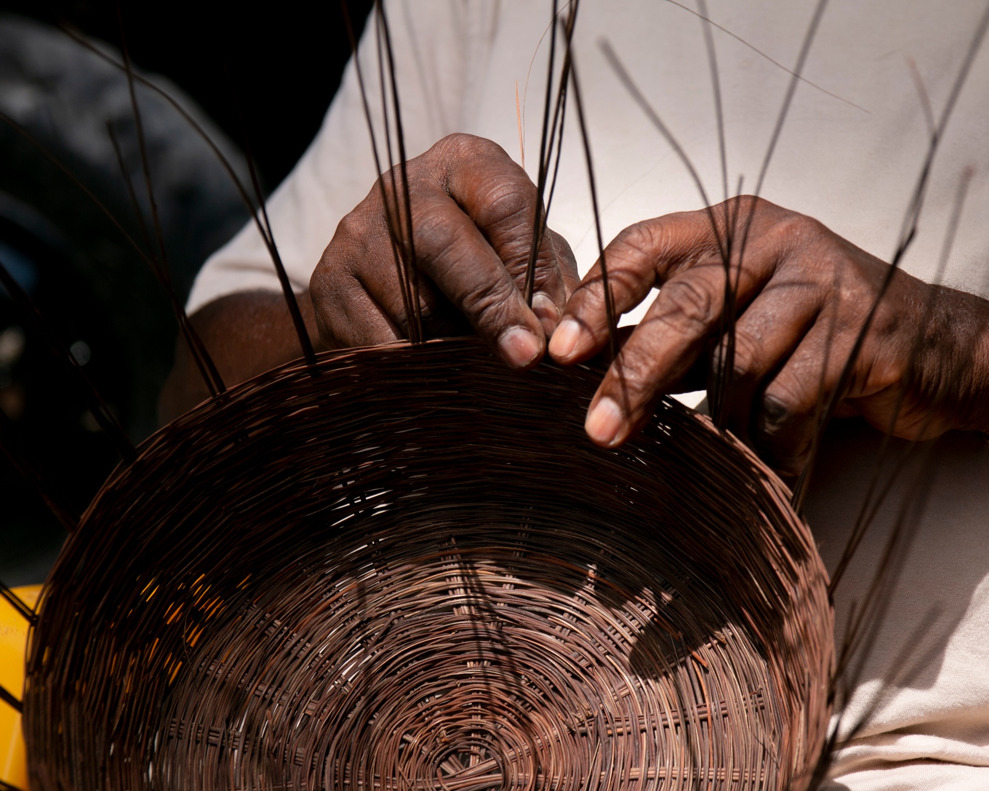 Cropped hand of person weaving a basket