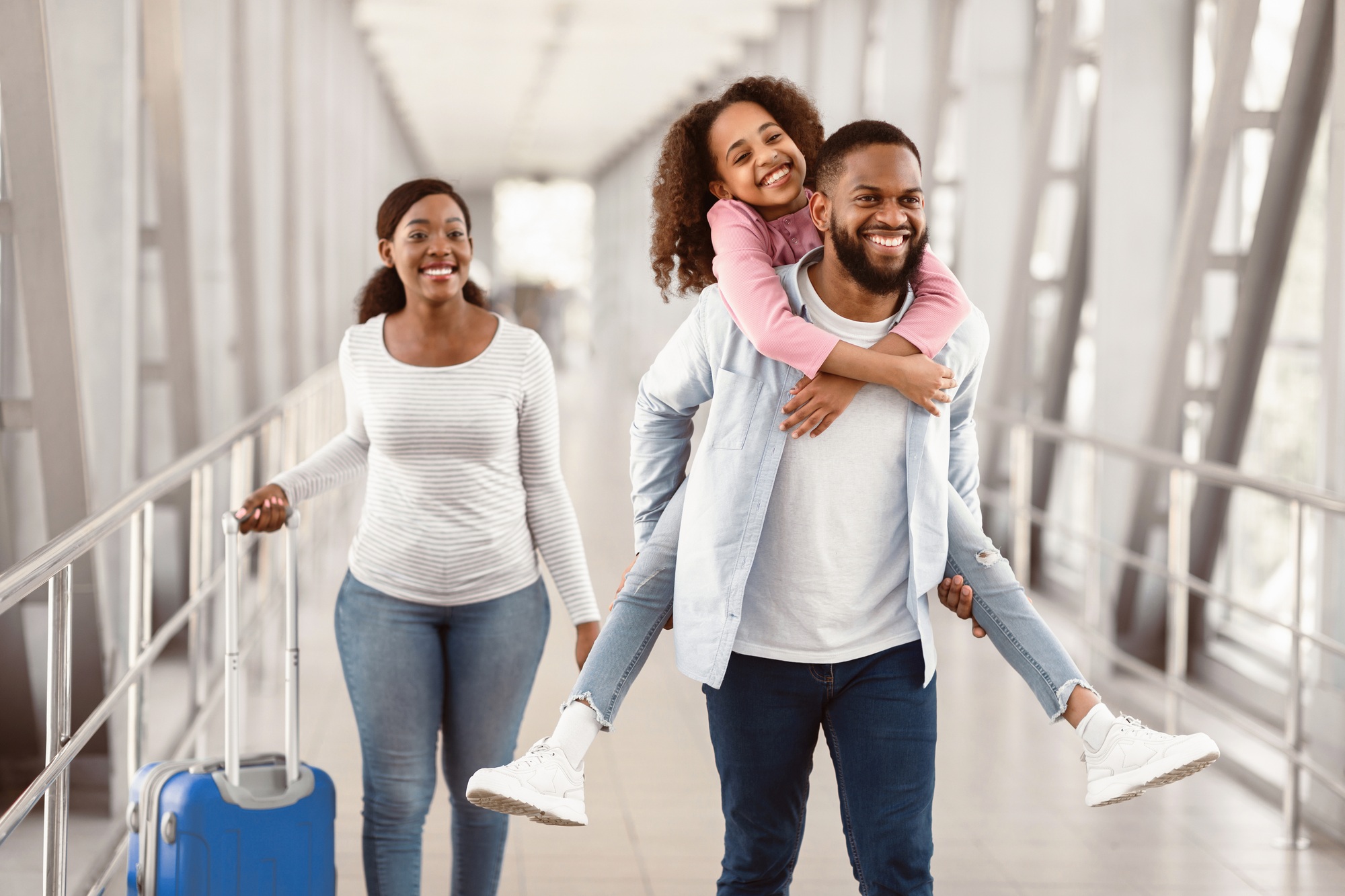 Happy black family traveling with kid, walking in airport