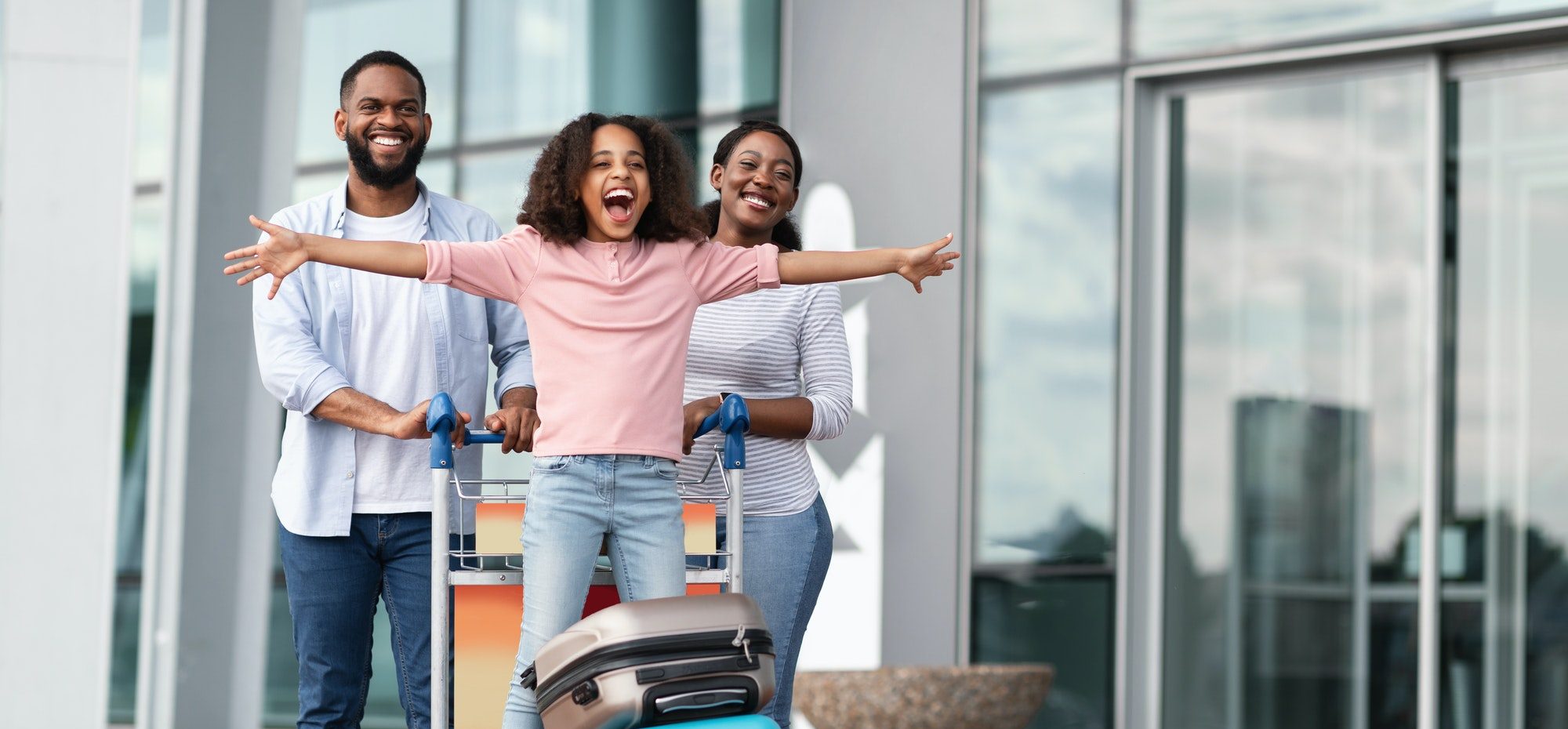 Happy black family traveling with kid, having fun in airport