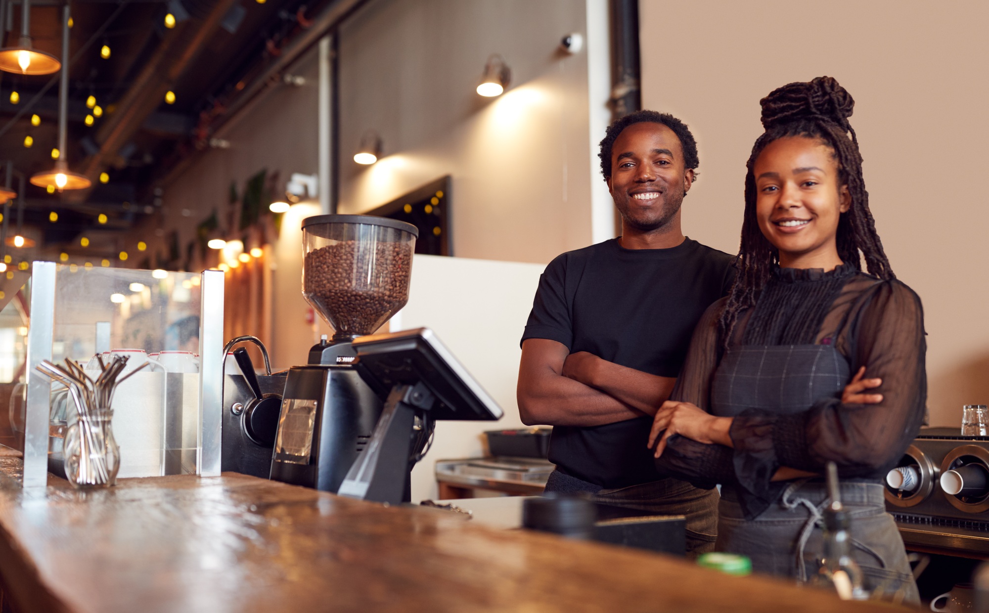 Portrait Of Male And Female Coffee Shop Owners Standing At Sales Desk